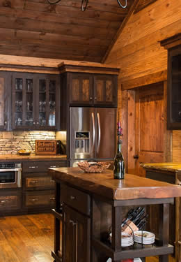 Craftsman custom wood stone kitchen dark brown timber cabinets light brown hardwood floors oversized drawers glass panel inset cabinet doors.